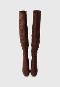 Καφέ μπότες μέχρι το γόνατο από σουέτ με λείο υφή, που διαθέτουν κομμένο δάκτυλο και κομψή σιλουέτα. Λεπτομέρεια φερμουάρ στο πλάι.