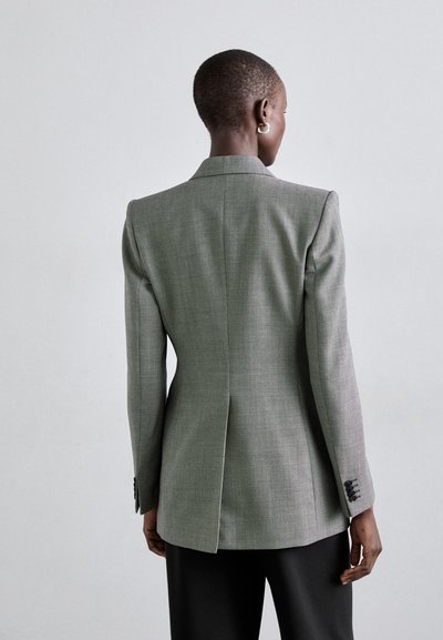 Harmaa teksturoitu bleiseri räätälöidyllä istuvuudella, lovilla varustettu kaulus, yksittäinen halkio takana ja nappikoristeet hihansuissa.