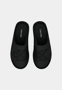 Pantofi negri tip slip-on cu logo-ul „CK” embosat. Confecționați din material neted, cu căptușeală interioară moale și talp�ă exterioară texturată.