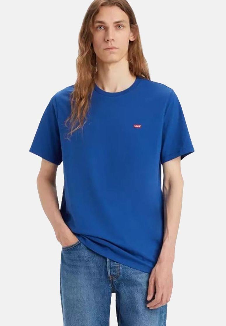 T-shirt en coton bleu à manches courtes et à col rond. Présente un petit logo rouge sur la poitrine. Porté avec un jean en denim bleu clair.