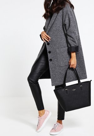 Grå uldfrakke med sort kant, sorte bukser i imiteret læder, pink sneakers og en sort tote-taske med gulddetaljer og logo.