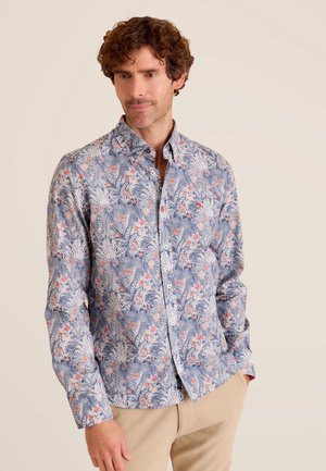 Chemise à imprimé floral aux couleurs bleu, blanc et corail, avec un design à boutons et des manches longues. Le tissu a une texture lisse.