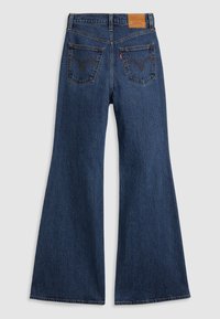 Jean en denim bleu foncé, taille haute, jambes larges, avec deux poches arrière ornées de détails cousus sur un fond uni.