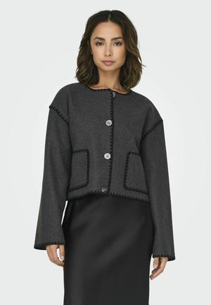 Cappotto corto in lana grigia con bordo scallopato, due tasche frontali e cinque grandi bottoni. Maniche lunghe e scollatura tonda.