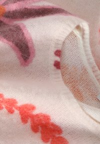 Adīta džemperis maigi rozā vilnā ar ziedu rakstiem rozā, oranžā un brūnā toņos. Iezīmējas ar ribotām malām un smalku faktūru.