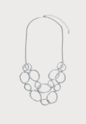 Collier chaîne en argent avec plusieurs anneaux métalliques martelés de forme ovale irrégulière reliés dans un design superposé et fermoir réglable.
