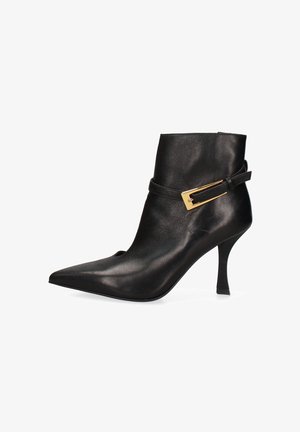 Stivale alla caviglia in pelle nera con punta appuntita, tacco a stiletto affusolato e un accento di fibbia dorata su una cinghia attorno alla caviglia.