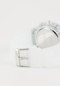 Clear silicone strap watch featuring a metallic silver buckle, transparent case, and engraved back with brand logo. Round face displays time.