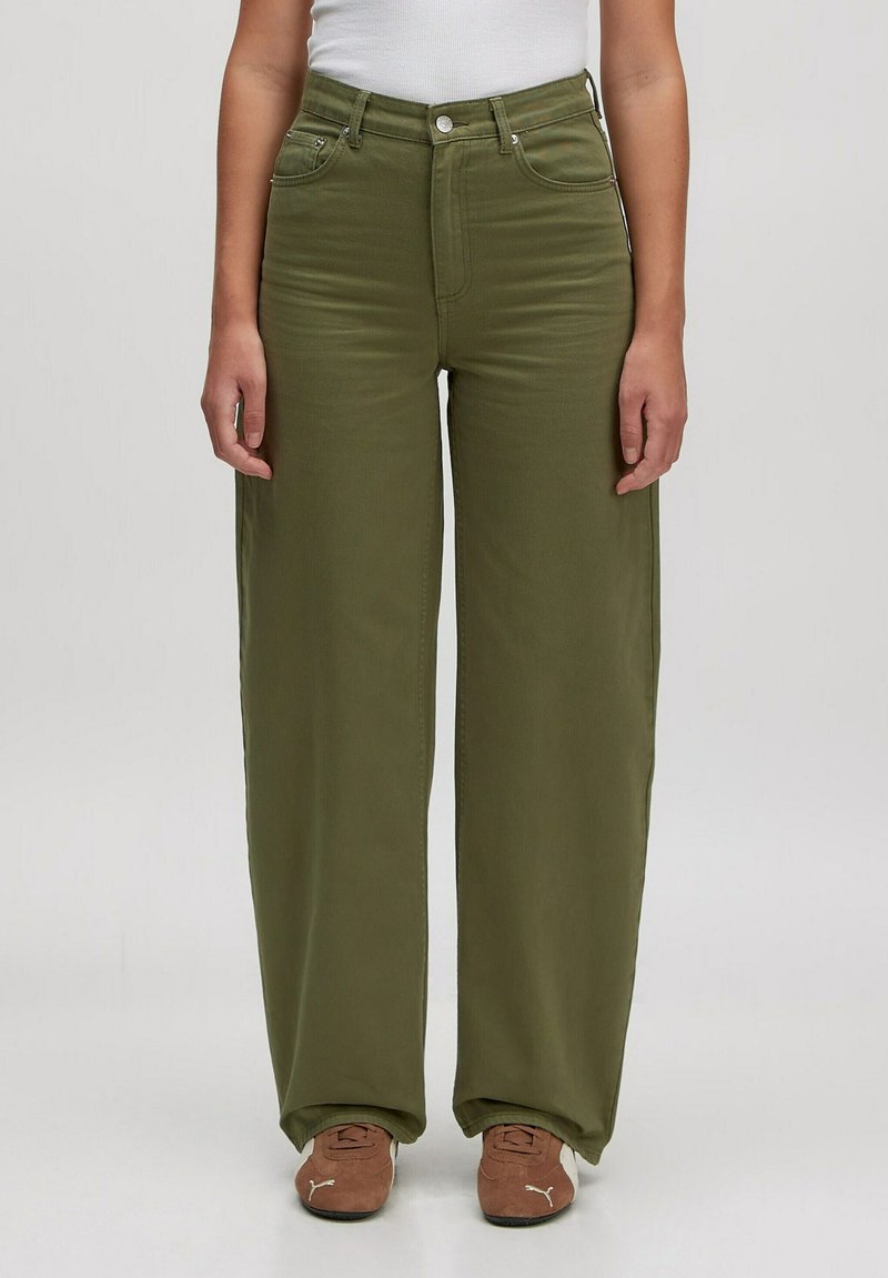 Wijdvallende olijfgroene jeans van een katoenmix. Voorzien van voorzakken, ritssluiting en knoopsluiting. Zachte textuur, gladde afwerking.