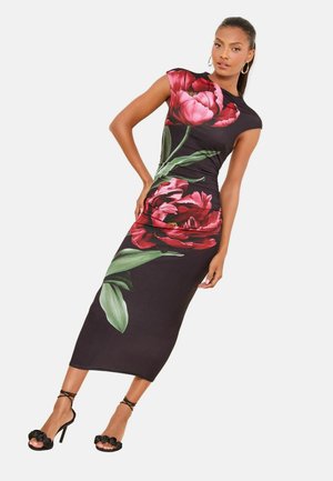 Schwarzes Blumenkleid mit großen roten Blumen und grünen Blättern. Glatter Stoff, figurbetonte Silhouette, kurze Ärmel und seitliche Raffdetails.