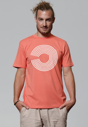 Koraalkleurig t-shirt van katoen, voorzien van een grafisch ontwerp van concentrische cirkels in het wit. Korte mouwen en een ronde hals.