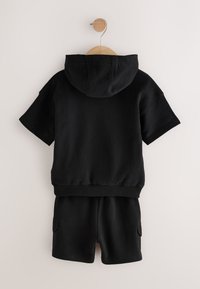 Black cotton hoodie with a large hood and short sleeves, paired with matching shorts featuring side pockets and an elastic waistband.