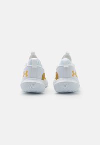 Chaussures de sport blanches avec un tissu en maille, des accents jaunes et des languettes à l'arrière. Semelles en caoutchouc texturé pour une meilleure traction.