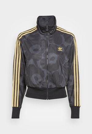 Zwarte Adidas trainingsjas met grijs bloemmotief, gele drie strepen op de mouwen en geel Adidas-logo op de borst, vooraan met rits en hoge kraag.