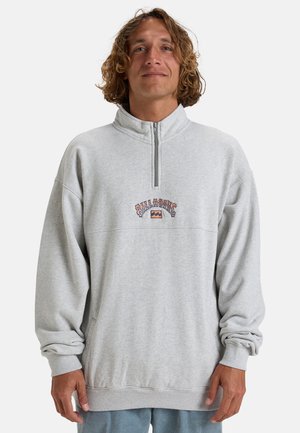 Pullover grigio in felpa con colletto alto, chiusura con zip e logo ricamato sul petto. Vestibilità ampia con polsini e orlo a costine.