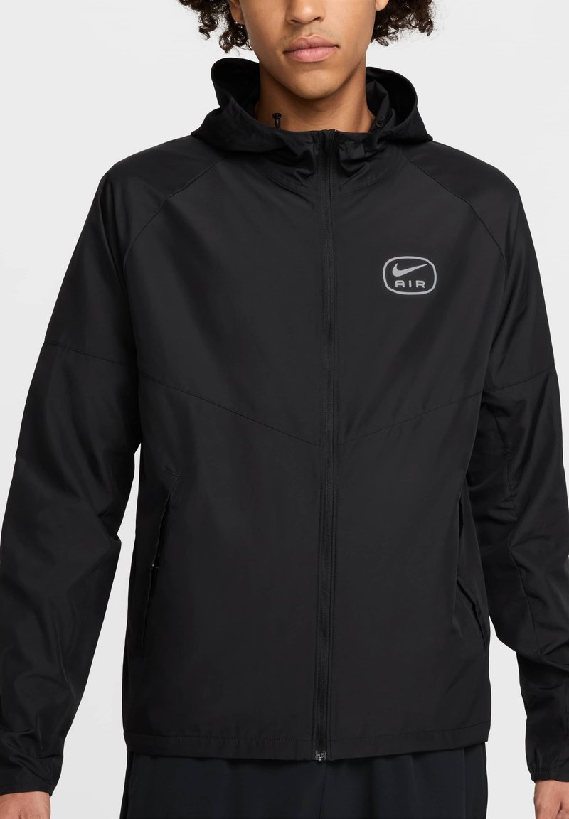 Black lightweight jacket made of smooth fabric, featuring a hood, front zipper, and Nike AIR logo on the left chest.