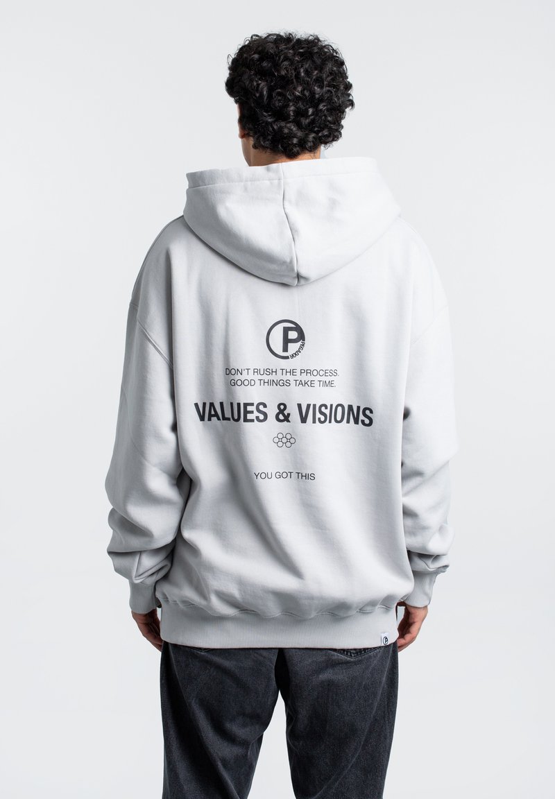 Jasnoszara hoodie wykonana z miękkiego materiału. Posiada dużą kaptur, ściągacze na rękawach oraz tekst na plecach, w tym "WARTOŚCI I WIZJE" napisany pogrubioną czcionką w czarnym kolorze.