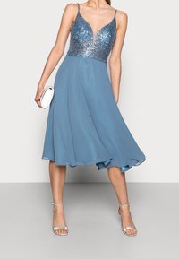 En blå A-linje klänning med en paljettsmyckad överdel, djup urringning, justerbara spaghettiband och en flödande chiffongkjol.