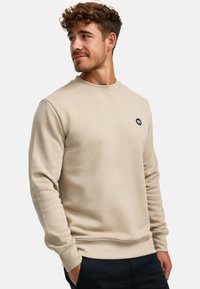 Beige Sweatshirt mit Rundhalsausschnitt aus weichem Stoff, featuring ribbed cuffs und Saum, mit einem kleinen dunklen Logo auf der Brust.