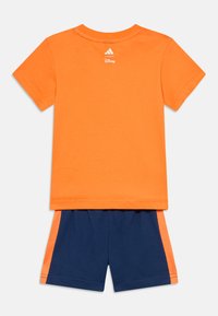 Πορτοκαλί βαμβακερό μπλουζάκι με στρογγυλή λαιμόκοψη και λογότυπο Adidas. Συνδυασμένο σκούρο μπλε σορτς με πορτοκαλί πλευρικές λεπτομέρειες και ελαστική μέση.