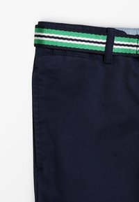 Pantaloni di cotone blu navy con una cintura intrecciata a righe verdi, bianche e nere. Il tessuto appare liscio con un design classico a gamba dritta.