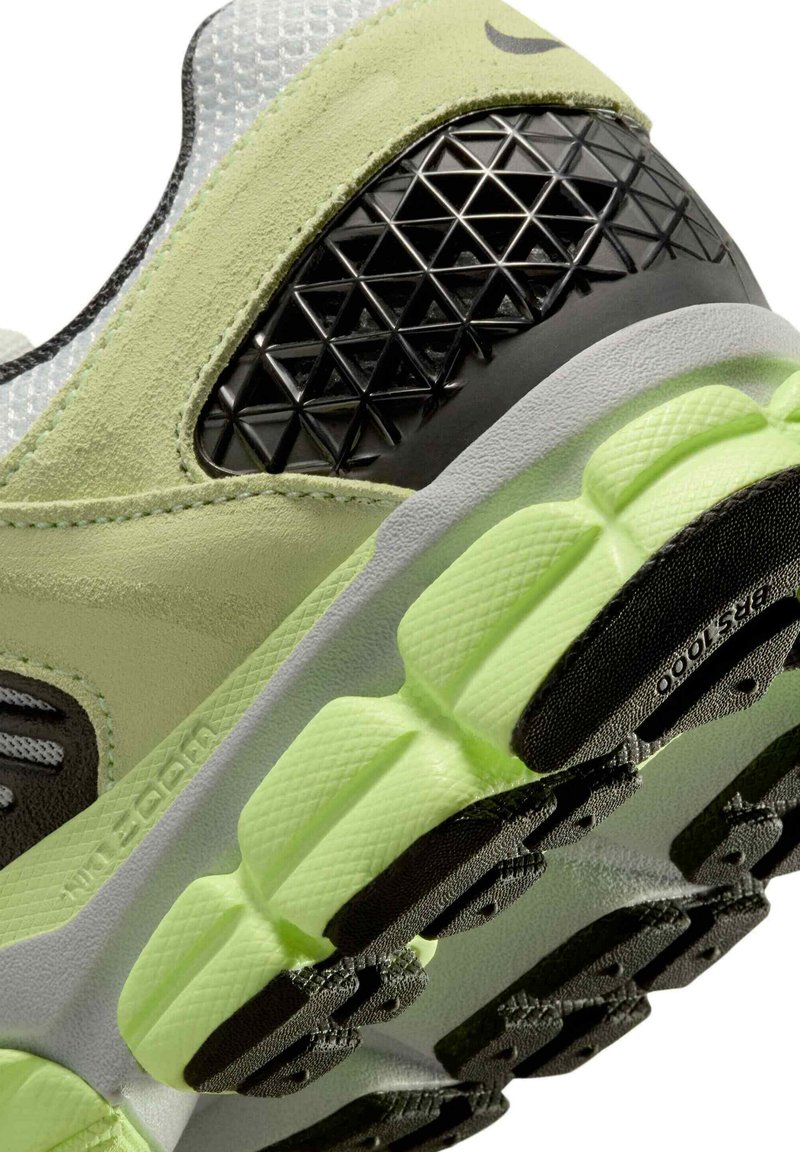 Zapatilla de running Nike con parte superior de malla y ante en verde claro, detalles texturizados en negro y una suela gruesa de color verde neón con un dibujo de patrón.