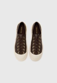 Bruine leren sneakers met gouden oogjes en donkerbruine veters. Voorzien van een crèmekleurige rubberen zool en een textuur patroon aan de zijkanten.
