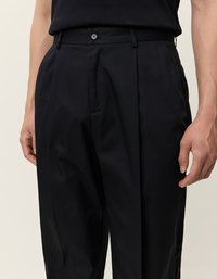 Mustad püksid siledast kangast, nupuga kinnitusega, volditud esiosa ja küljetaskutega. Kohandatud lõige puhta viimistlusega.