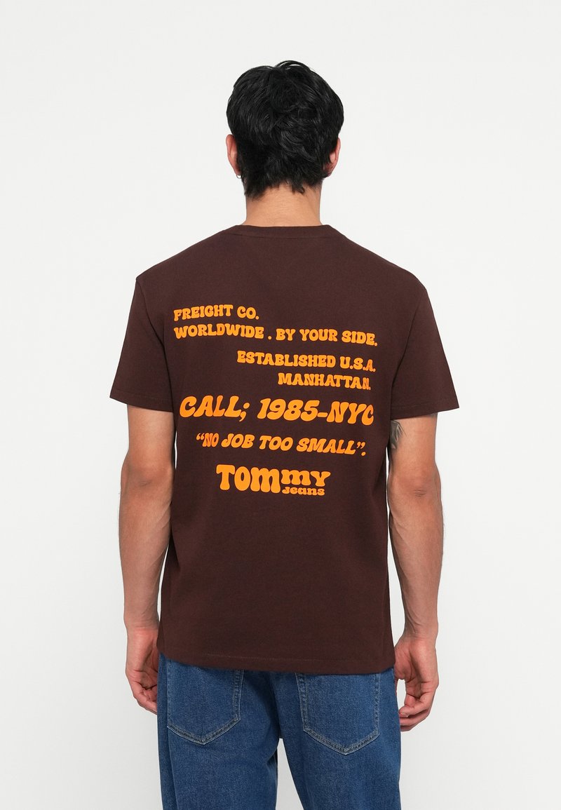 T-Shirt din bumbac marron cu text retro portocalie pe spate. Are inscripțiile "FREIGHT CO." și "TOMMY" în partea de jos. Mâneci scurte, design cu guler rotund.