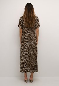 Robe maxi à imprimé léopard avec manches courtes, présentant une silhouette fluide en beige et noir, tissu texturé, longueur mi-mollet.