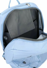 Mochila azul claro con apertura con cremallera, interior gris y bolsillo adicional. Presenta una textura suave y herrajes a juego.