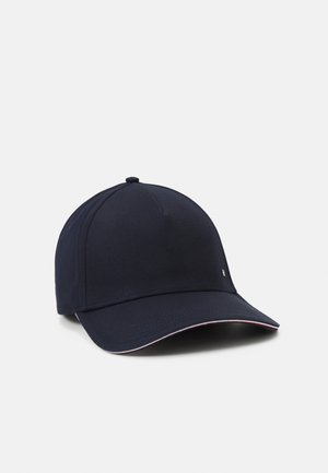 Casquette de baseball bleu marine à visière courbée avec de petits détails blancs et rouges sur le bord, présentée sur un fond clair uni.