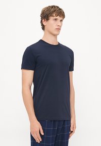 Tricou bleumarin cu mânecă scurtă, confecționat dintr-un material moale din bumbac, cu guler rotund, design ajustat și textură fină.