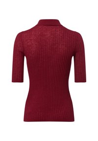 Polo rouge côtelé avec manches courtes, texture douce et silhouette ajustée avec un col subtil.