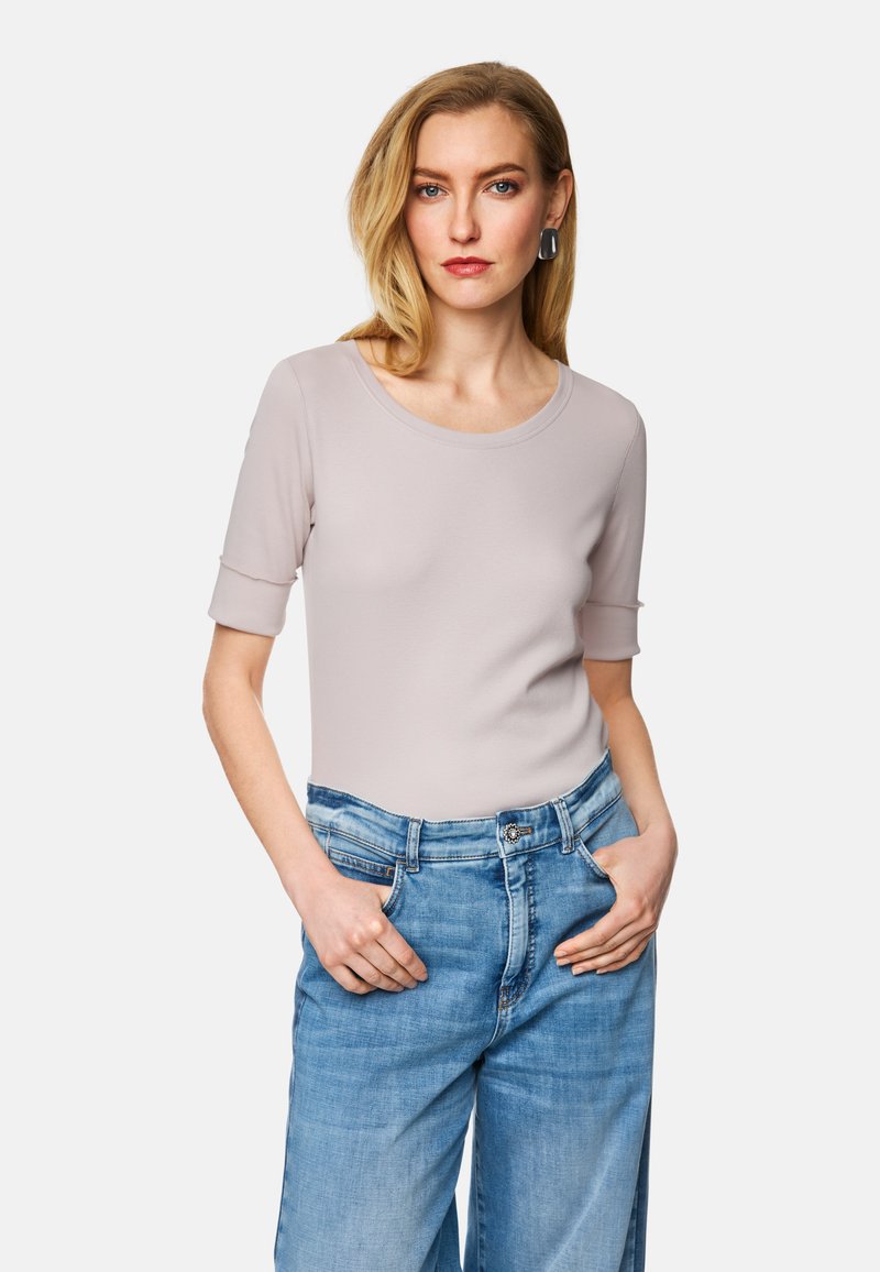 Helles beige Kurzarmoberteil mit Rundhalsausschnitt, kombiniert mit hellblauen, weiten Jeans. Weicher Stoff, schlichtes Design.