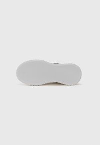 Sko såle med en teksturert, rilleformet overflate, hovedsakelig hvit, med en avrundet form og minimalistisk design uten ekstra dekorasjoner.