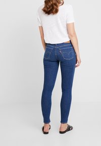 Smala jeans i mörkblå denim, med hög midja, fem fickor och broderad design på baktill med en lädermärke.