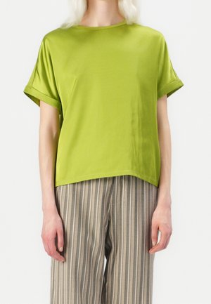 Haut vert à manches courtes avec finition satinée et coupe décontractée, accompagné d'un pantalon gris à larges rayures et jambes larges, présentant un design casual.