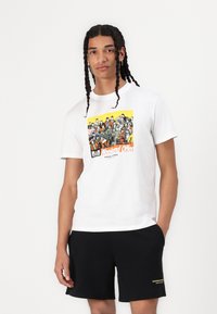 White cotton t-shirt featuring a colorful graphic print with the text "Weekend Offer" on a yellow background. Paired with black shorts.