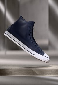 Adidași înalți din piele bleumarin, cu talpă din cauciuc alb, accente texturate și design clasic cu șireturi. Prezintă un vârf rotund și dungi albe.