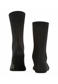 Chaussettes noires côtelées fabriquées à partir d'un matériau texturé. Présentent un talon et un orteil renforcés, avec une marque sur la semelle près du talon.