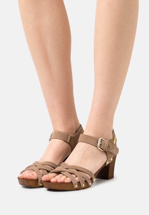 Brown suede high-heeled sandals feature a strappy design, open toe, ankle strap with buckle, and a textured wooden heel.
