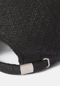 Căciulă neagră cu textură, având un aspect împletit, prevăzută cu un sistem de ajustare metalic și o margine curbă.
