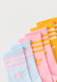 Βαμβακερές κάλτσες σε ανοιχτό μπλε, ροζ και κίτρινο με οριζόντιες ρίγες. Κάθε ζευγάρι έχει διακριτικό λογότυπο στο ύψος του αστραγάλου. Με υφασμένο ριμπ σχέδιο.