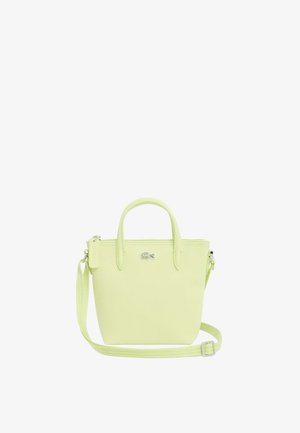 Pequeña bolsa tote de color verde claro con dos asas, correa ajustable para el hombro, cierre con cremallera y logo de cocodrilo de Lacoste en el frente.