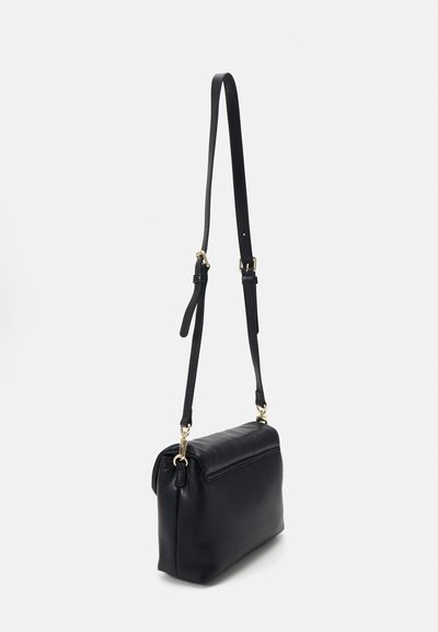 Borsa a tracolla in pelle nera con tracolla regolabile e hardware dorato, mostrata appesa su uno sfondo bianco semplice.