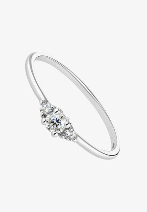 Anillo de metal plateado con un diamante redondo central y dos diamantes redondos más pequeños a cada lado; acabado elegante y pulido.