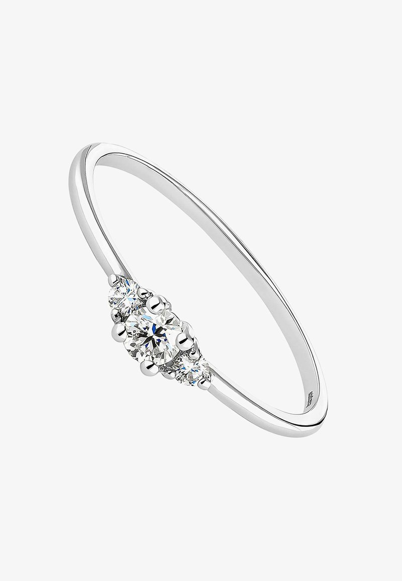 Anillo de metal plateado con un diamante redondo central y dos diamantes redondos más pequeños a cada lado; acabado elegante y pulido.