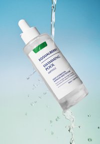Przezroczysta szklana ampułka z białą nakrętką z zakraplaczem; opatrzona etykietą "EQUALBERRY BASEN". Zawiera 50ml nawilżającego serum, z chlapiącą wodą wokół.
