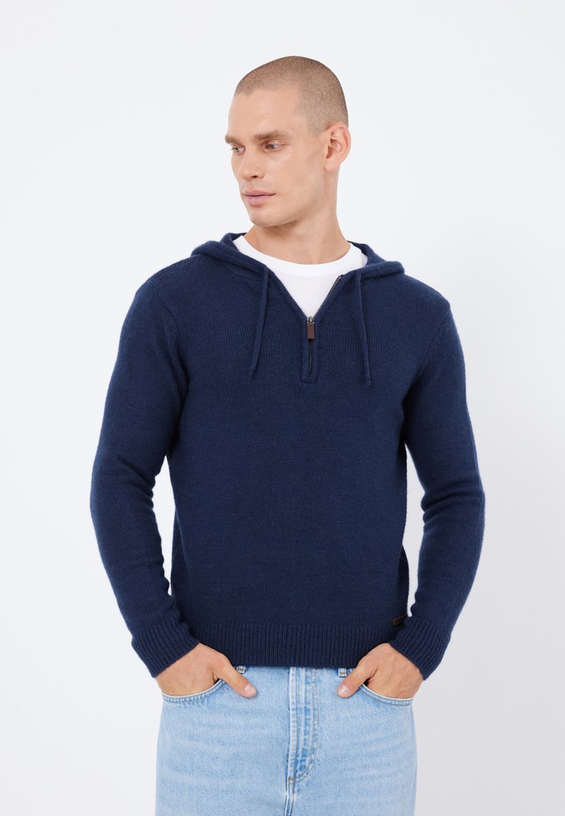 Marineblaue Fleece-Hoodie mit einem halben Reißverschluss an der Vorderseite, Kordelzugkapuze, gerippten Bündchen und Saum, getragen über einem weißen T-Shirt. Klassische Passform.